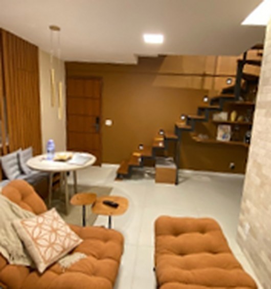 Sala depois do projeto, com ripado de madeira, escada nova e sofás terracota